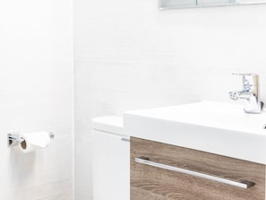 Ein Badezimmer mit einem weißen Waschbecken, einer Toilette und einem Handtuchhalter.