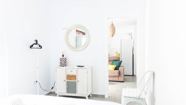 A modern, white-themed bedroom with a bed, a dresser, a mirror, and a hanging lamp. - Casa Rehala Paya by Cadiz Time (Cádiz)