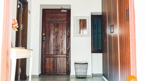 A hallway with a wooden door, a small round table, and a cabinet. - Casa Rehala Paya by Cadiz Time (Cádiz)