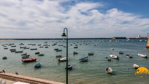A coastal scene with numerous small boats anchored in calm waters, a clear sky, and a distant shoreline with buildings. - La Roca del Sur by Cadiz Time (Cádiz)