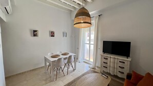 A modern living room with a dining area, a television, and a large window. - La Roca del Sur by Cadiz Time (Cádiz)