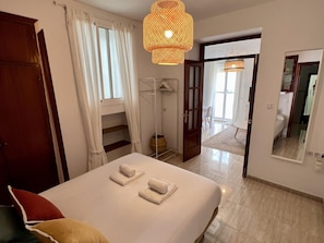 A hotel room with a bed, a wardrobe, a mirror, and a hallway leading to another room. - La Roca del Sur by Cadiz Time (Cádiz)