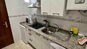 A compact kitchen with white cabinets, a microwave, a sink, and a dishwasher. - La Roca del Sur by Cadiz Time (Cádiz)