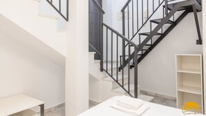 Um interior moderno com escada, paredes brancas e chão de mármore.