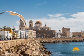 A coastal cityscape with historic architecture, a stone seawall, and a clear blue sky. - Loft Santa Maria by Cadiz Time (Cádiz)
