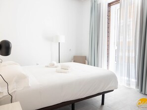 Una habitación de hotel moderna con una cama grande, una lámpara de noche y una silla.