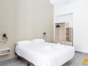 Un dormitorio moderno con una cama grande, un armario y una lámpara fijada a la pared.
