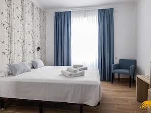 A bedroom with a bed, pillows, a chair, and a window with curtains. - La Luz de La Vi a Free Parking by Cadiz Time (Cádiz)