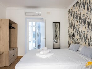 A bedroom with a large bed, a wooden wardrobe, a mirror, and a patterned wallpaper. - La Luz de La Vi a Free Parking by Cadiz Time (Cádiz)