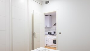 Een slaapkamer met een bed, een badkamer met toilet en een kitchenette met een magnetron.