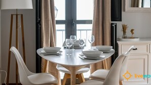 Een eetgedeelte met een ronde tafel voor vier personen, omringd door witte stoelen.