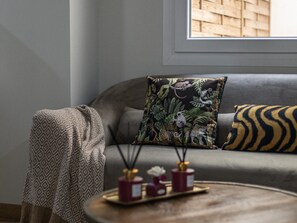 A living room with a grey sofa, a patterned throw blanket, a decorative pillow with a jungle print, and a small table with two candles and a vase. - Writer s Home by Cadiz Time (Cádiz)