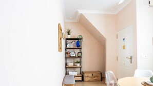A cozy room with a wooden bench, a clear plastic chair, a round wooden table, and a bookshelf with various items. - Corralon de Los Carros by Cadiz Time A (Cádiz)