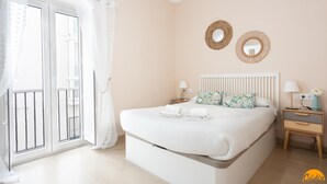 A bedroom with a bed, two nightstands, a window with curtains, and two wall-mounted mirrors. - Corralon de Los Carros by Cadiz Time A (Cádiz)