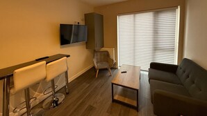Ein Wohnzimmer mit Fernseher, einer Couch, einem Couchtisch und einem Sessel.