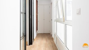 A corridor with a door at the end, large windows on one side, and a tiled floor. - Mar de La Vi a Free Parking by C diz Time (Cádiz)