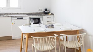 A modern kitchen with white cabinets, a wooden dining table, and two white chairs. - Mar de La Vi a Free Parking by C diz Time (Cádiz)