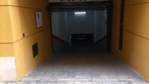 A narrow hallway with yellow walls and a textured floor leading to a door with a patterned window above it. - Mar de La Vi a Free Parking by C diz Time (Cádiz)