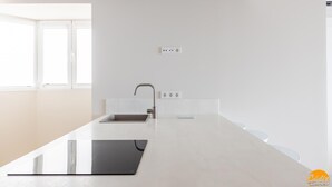 A modern kitchen with a large island, a sink, and a window providing natural light. - Malibu by Cadiz Time (Cádiz)