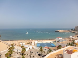 A coastal cityscape with a beach, a sailboat, and a basketball court. - Malibu by Cadiz Time (Cádiz)