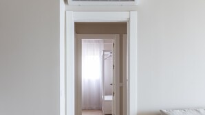 A hallway leading to a bathroom with a shower, a door, and a light switch on the wall. - Malibu by Cadiz Time (Cádiz)