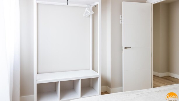A bedroom with a white wardrobe, a bed with a white duvet, and an air conditioning unit on the wall. - Malibu by Cadiz Time (Cádiz)