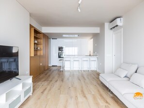A modern living room with a flat-screen TV, a white sofa, and a wooden shelving unit. - Malibu by Cadiz Time (Cádiz)