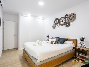 Ein Schlafzimmer mit einem hölzernen Bett, weißer Bettwäsche und einer Wanduhr.