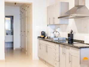 Una cocina moderna con armarios blancos, una campana de acero inoxidable, una cafetera y un fregadero con un bloque para cuchillos.