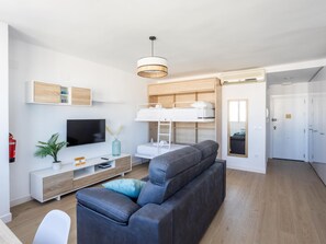 Una sala de estar moderna con un sofá gris, un televisor, una cama litera y un diseño minimalista.