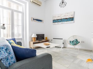 A modern living room with a sofa, a coffee table, a TV, and a chair. - Mar de Cadiz by Cadiz Time (Cádiz)