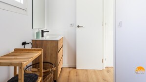 Een moderne badkamer met een witte wastafel, een houten wastafelmeubel en een spiegel.