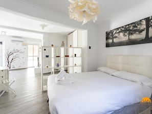 Ein modernes Hotelzimmer mit einem großen Bett, einem weißen Schrank und einem Baumgemälde.