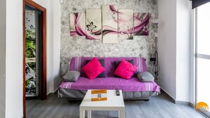 A modern living room with a purple sofa, a white coffee table, and a wall with three abstract floral paintings. - Modern Haven Loft by Cadiz Time (Cádiz)