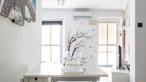 A modern kitchen with a central island, white cabinetry, and a decorative tree mural on the wall. - Modern Haven Loft by Cadiz Time (Cádiz)