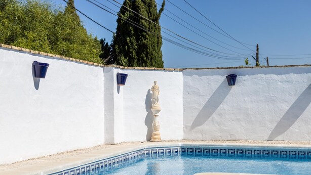 A swimming pool with a statue in the center, surrounded by white walls and blue tiles. - Frambuesa by Cadiz Time (Chiclana de la Frontera)