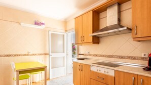 A kitchen with wooden cabinets, a stove, and a dining table with chairs. - Frambuesa by Cadiz Time (Chiclana de la Frontera)