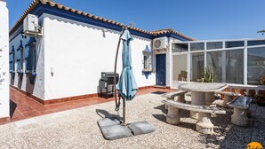 A patio area with a stone table and chairs, a blue umbrella, and a water fountain. - Frambuesa by Cadiz Time (Chiclana de la Frontera)