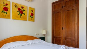 A hotel room with a bed, a wooden wardrobe, and three paintings of roses on the wall. - Frambuesa by Cadiz Time (Chiclana de la Frontera)