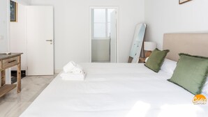 Een hotelkamer met een bed, een bureau, een spiegel en een deur naar een badkamer.