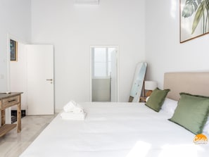 Habitación de hotel con cama, escritorio, espejo y puerta que da a un baño.