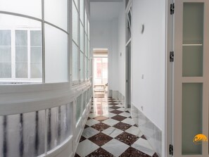 A corridor with a checkered floor, white walls, and a glass door. - Casa Amanecer by Cadiz Time (Cádiz)