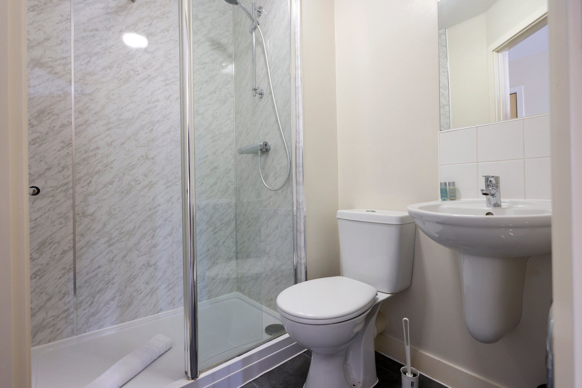 Un baño con ducha de vidrio, inodoro blanco y lavamanos.