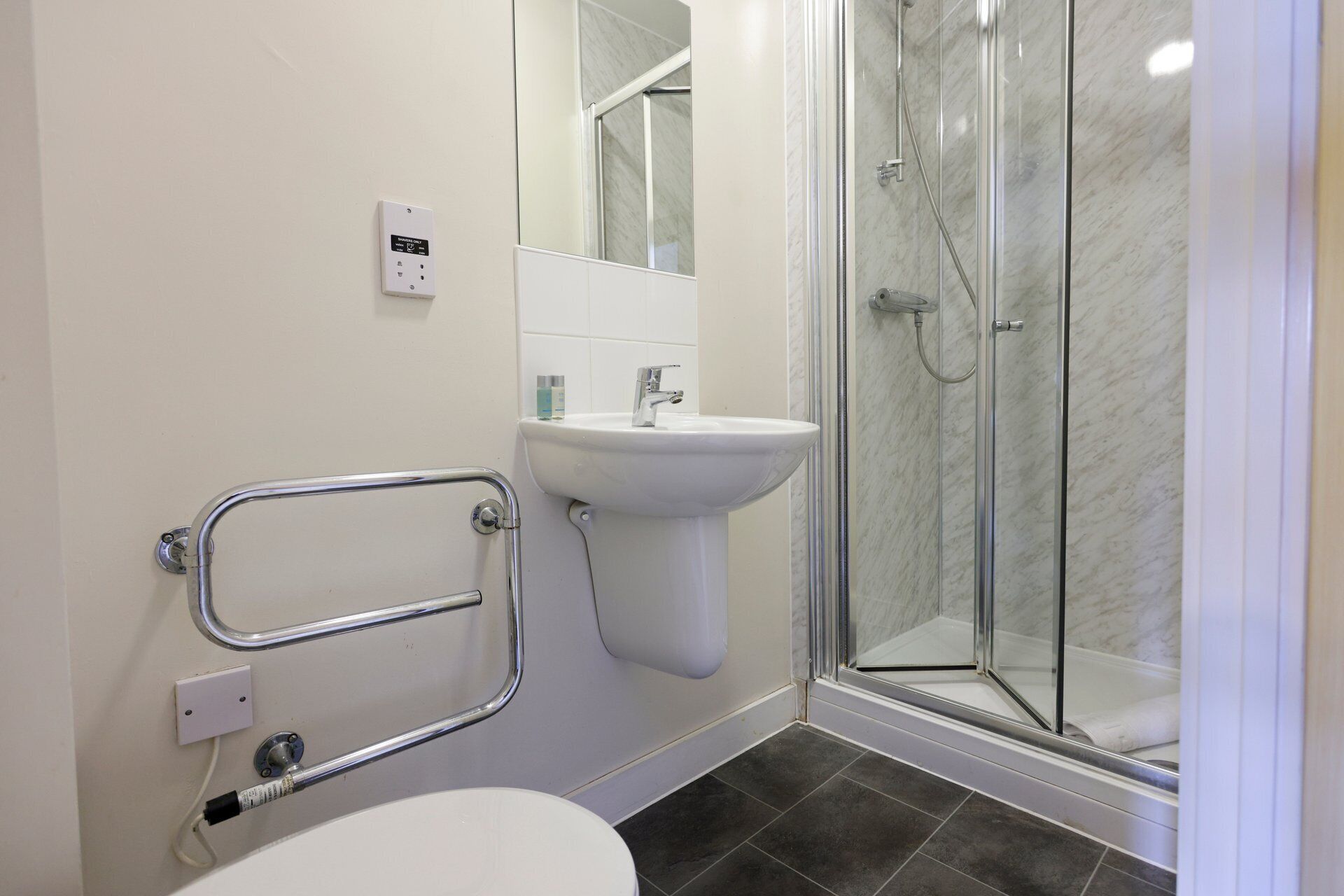 Une salle de bain équipée d’une douche, d’un lavabo, de toilettes et d’une barre d’appui.