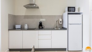 A modern kitchen with a built-in microwave, a coffee maker, a kettle, and a refrigerator. - Delfin Azul 3 by Cadiz Time (Cádiz)