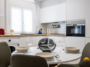 Eine moderne Küche mit weißen Schränken, einer Holz Arbeitsplatte und einem Esstisch, gedeckt mit Tellern, Gläsern und Besteck.