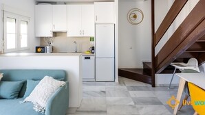 Une cuisine moderne avec des meubles blancs, un four encastré et une machine à café.