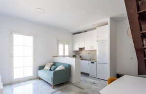 Un espace de vie compact comprenant un coin cuisine, un canapé et un coin repas.