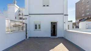 Un bâtiment blanc doté d’un toit plat, d’une petite entrée et d’une terrasse en briques.