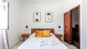 Une chambre d’hôtel comprenant un lit, deux tables de chevet, une armoire en bois et deux œuvres d’art abstraites accrochées au mur.